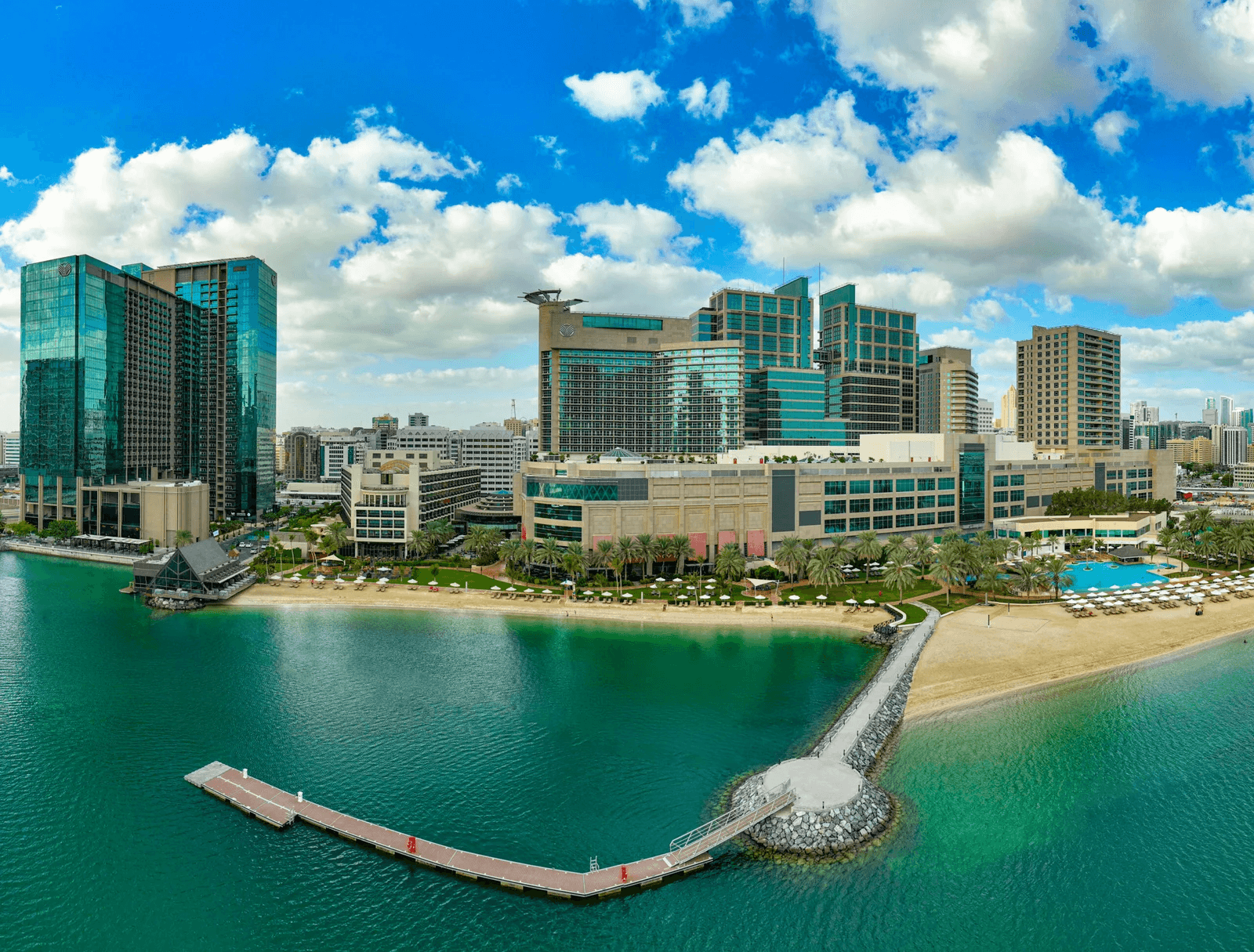 Waterfront resort with beach and pier under a bright sky